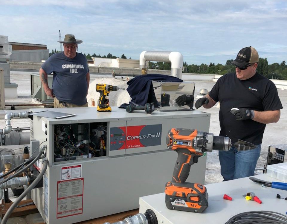 Two technicians from Cummings Inc. servicing a commercial rooftop HVAC unit in Puyallup, WA.