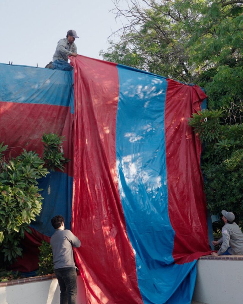 Technicians setting up a large red and blue tent for termite fumigation by San Joaquin Pest Control in Fresno, CA.