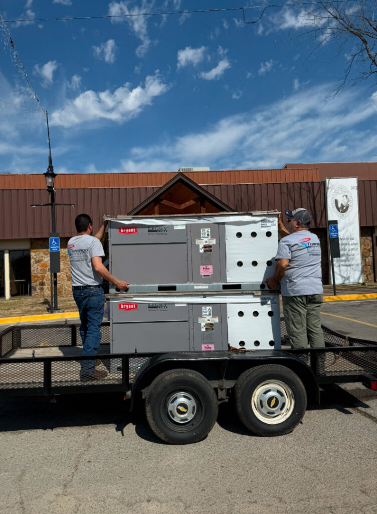 Tornado Heating and Air technicians unloading new Bryant HVAC units from a trailer in Tulsa, OK.