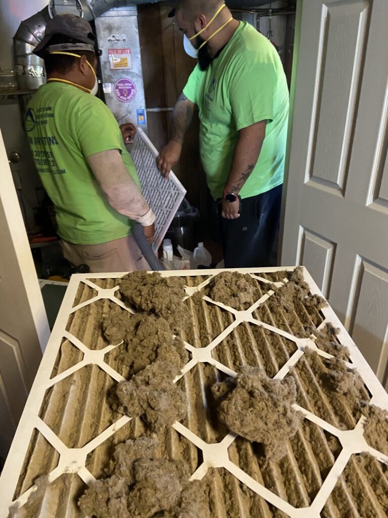 Clean Air Solutions technicians inspecting a very dirty air filter during an HVAC service in Gaithersburg, MD.