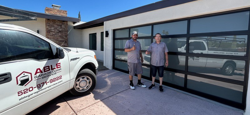 Able Garage Door Service, LLC technicians proudly stand by a newly installed modern glass garage door in Tucson, AZ.