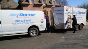 Two Air Doctor Duct Cleaning & Lining technicians with their service van and trailer in Tulsa, OK, preparing for a job.