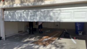 Two technicians working on a garage door installation or repair inside a garage for Olympus Garage Door Repair in Tempe, AZ.