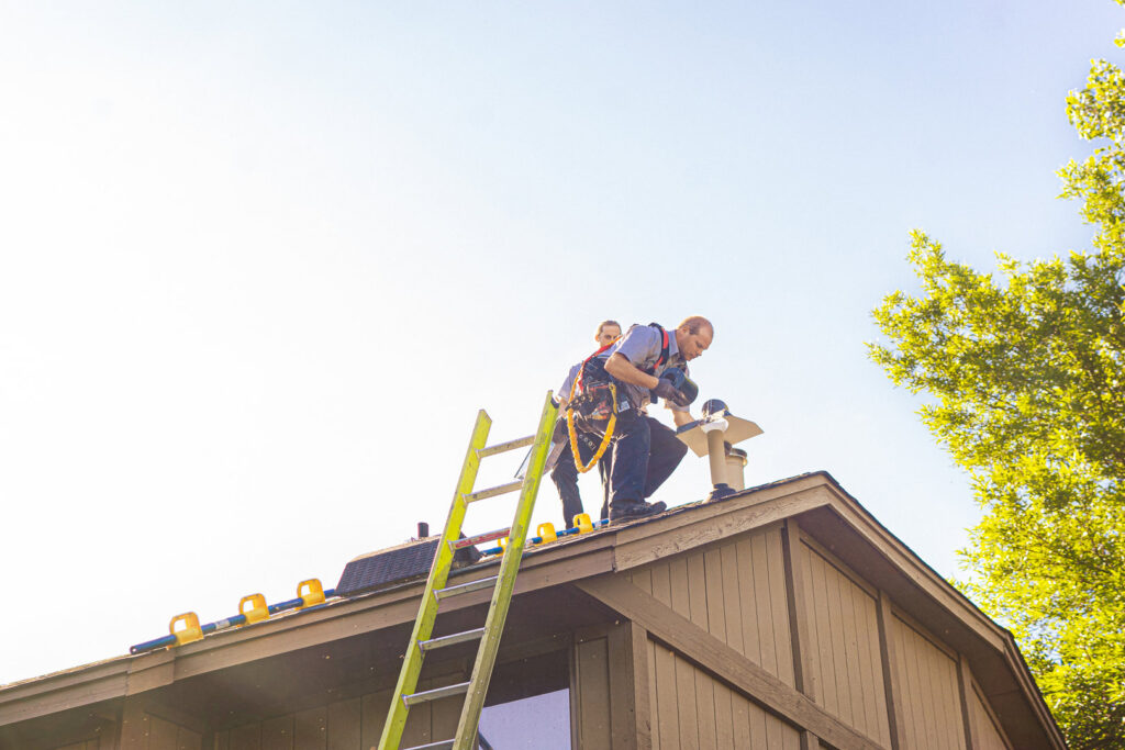 Two technicians working on a roof chimney for wildlife exclusion at Abra Kadabra Pest and Wildlife in Forest Lake, MN.