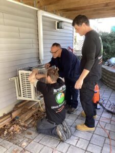 Three Heat Pump Pros technicians working on an outdoor mini-split heat pump unit in Hartford, CT.