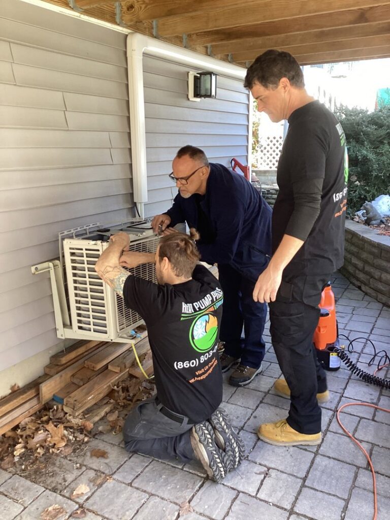 Three Heat Pump Pros technicians working on an outdoor mini-split heat pump unit in Hartford, CT.