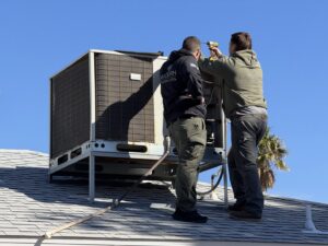 Two Modern Air Conditioning & Heating technicians performing maintenance on a rooftop HVAC unit in Boulder City, NV.