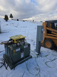 A temporary power setup with a generator and electrical meter in a snowy field by Trademark Elite Electrical Services in Butte, MT