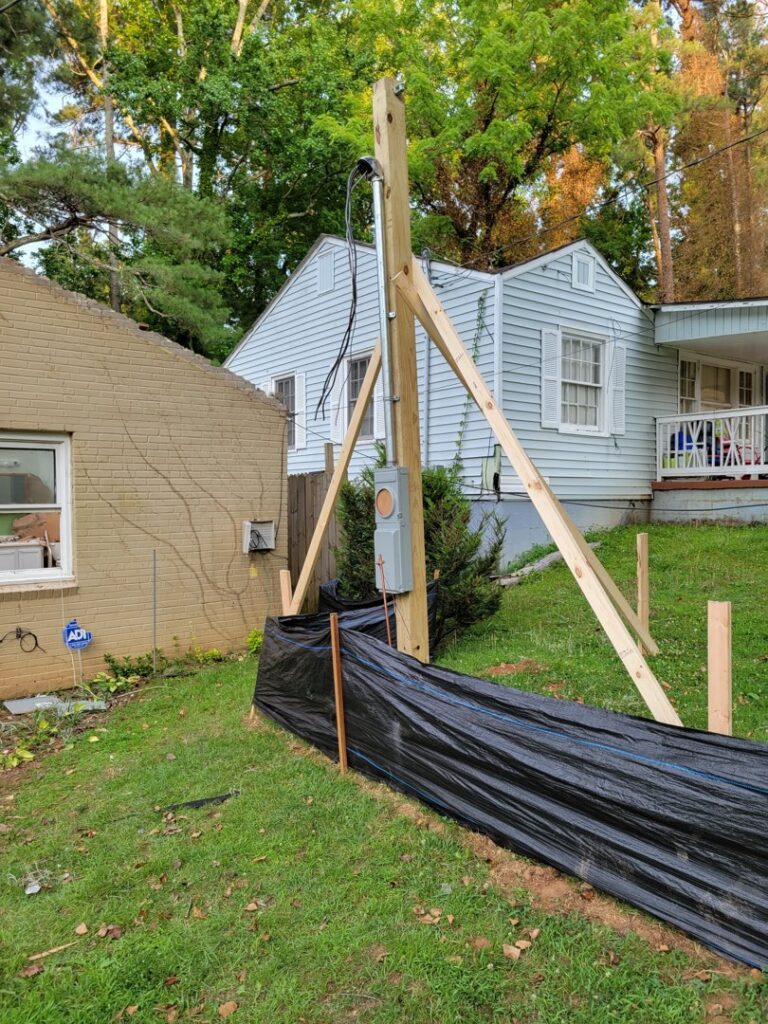 A temporary power pole with an electrical meter and conduit installed, showcasing work by 8Thirty Electric, Inc. in Johns Creek, GA.