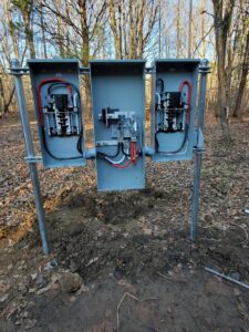 Temporary power pole installation with three electrical panels in a wooded area by Discount Electrical Service of Franklin in Franklin, TN