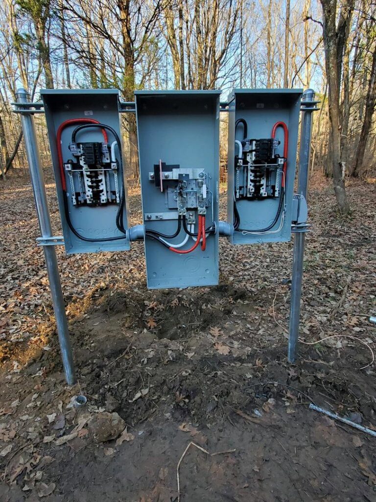 Temporary power pole installation with three electrical panels in a wooded area by Discount Electrical Service of Franklin in Franklin, TN