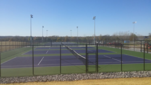 Black chain-link fence enclosing multiple tennis courts installed by Van's Fence in Kansas City, MO.