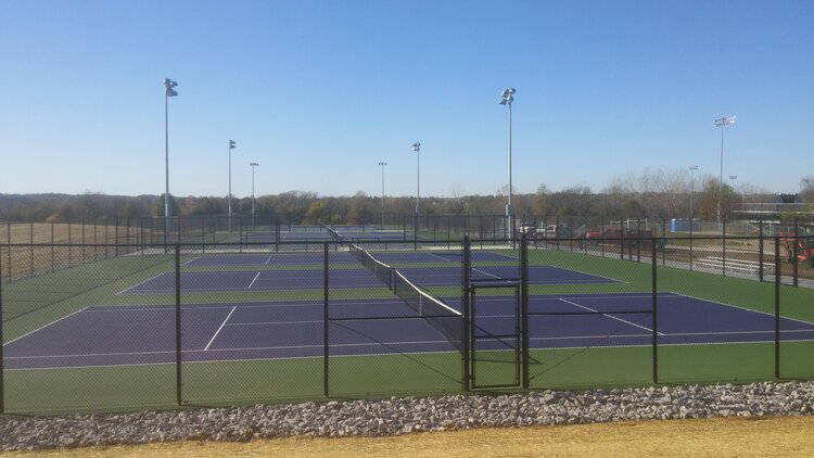 Black chain-link fence enclosing multiple tennis courts installed by Van's Fence in Kansas City, MO.