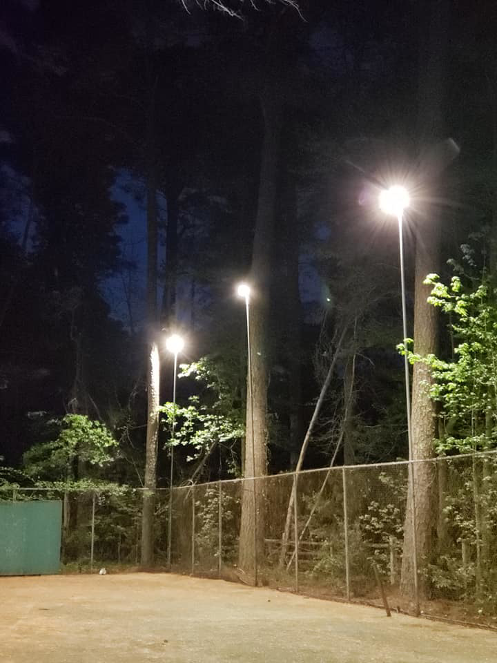 Tall pole lights illuminating a tennis court at night, installed by KC Electric in Pompton Plains, NJ.