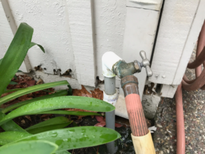 Close-up of termite damage on a house foundation near a water spigot, indicating pest control needs by Innova Termite in San Jose, CA.