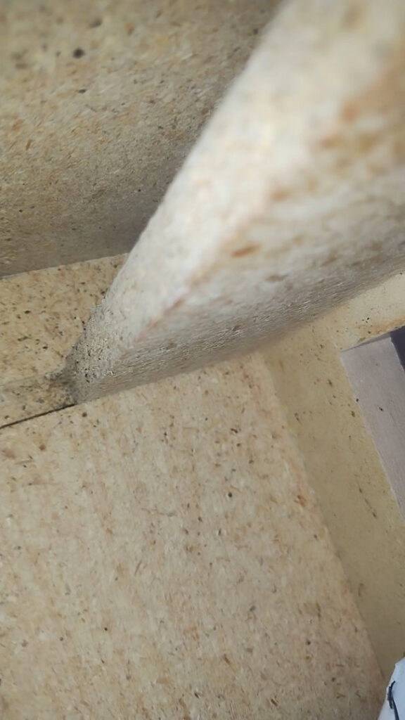 Close-up of termite frass or pest debris on a wooden beam, indicating a pest control service need from Termagon in Tucson, AZ.