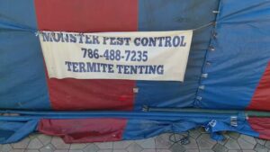 A close-up of the Monster Pest Control banner on a house tented for termite treatment in Miami, FL.