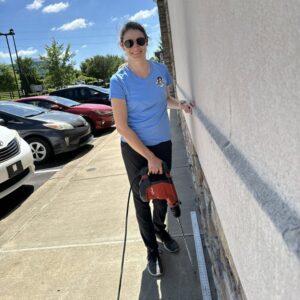 A Berner Pest Solutions team member drilling holes for termite treatment around a building foundation in Lexington, KY.