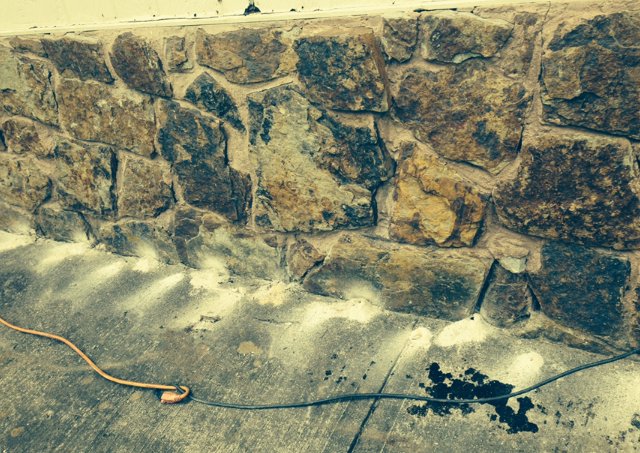 Termite treatment being applied to a stone foundation by Roach's Termite Service Inc. in Oklahoma City, OK
