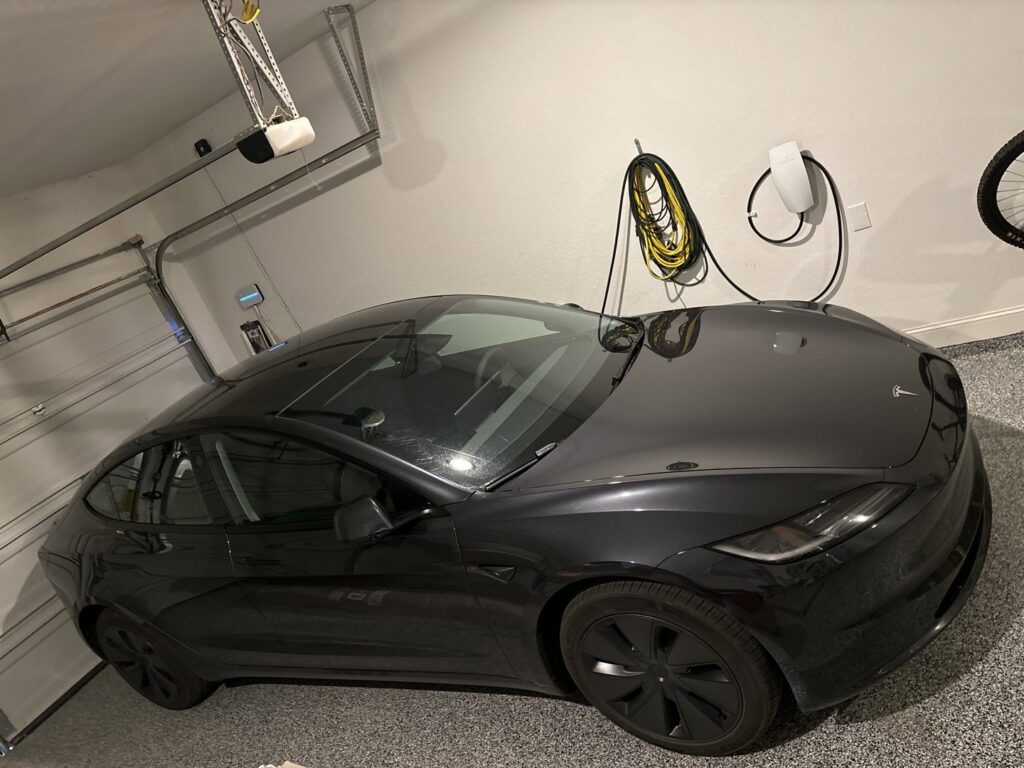 A Tesla car charging in a garage, showcasing a professionally installed EV charger by Davis Electric in Cleveland, OH.