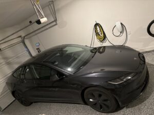 A Tesla car charging in a garage, showcasing a professionally installed EV charger by Davis Electric in Cleveland, OH.