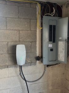 A Tesla EV charger installed next to an open electrical panel by ChargerPro in Denver, CO.