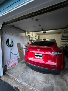 A red Tesla car charging with an EV charger installed by Henelect Electrical Contractors in Milford, NJ.