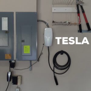 A Tesla EV charger and electrical panels professionally installed in a garage by Fuller Electrical Contractors, Inc. in Oldsmar, FL.