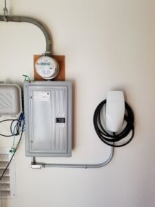 A Tesla electric vehicle charger installed next to an electrical meter and breaker panel by Wisdom Electrical in San Francisco, CA.