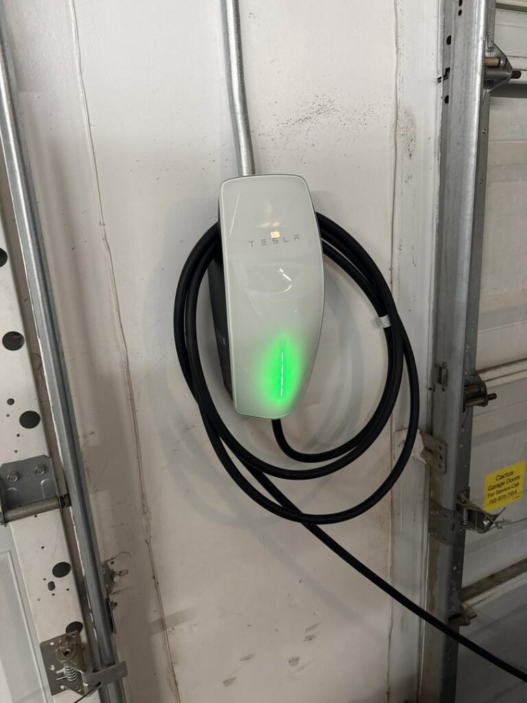A Tesla EV charger installed in a residential garage, a service provided by Big Red Electric Company in San Antonio, TX.