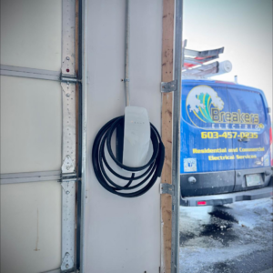 Tesla EV charger installation by Breakers Electric LLC in Dover, NH, with a service van in the background.