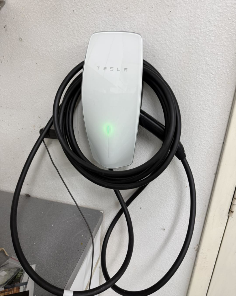 A Tesla electric vehicle charger installed on a wall by Down The Road Electric Inc in Iowa City, IA