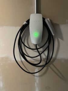 A Tesla EV charger professionally installed on a garage wall by Esmeralized Electric in San Jose, CA.