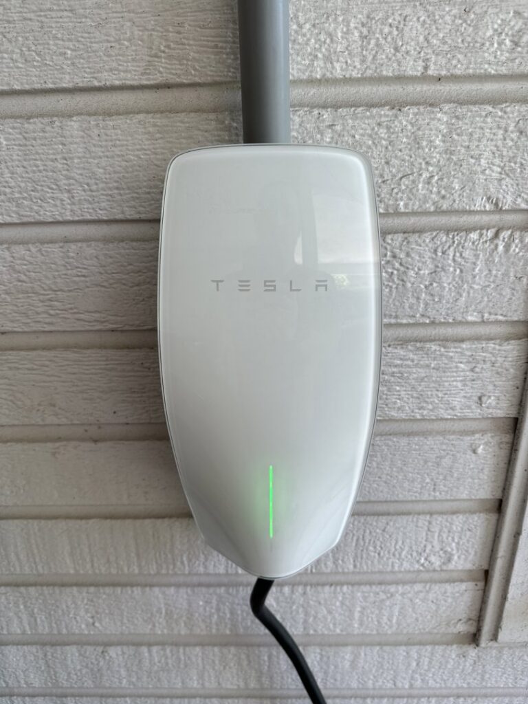 A Tesla EV charger installed on an exterior wall by Steadfast Electric, LLC in Baton Rouge, LA.
