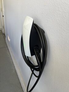 A Tesla EV charger professionally installed on a garage wall, ready for use, by AAA Electrical Services in Sacramento, CA.