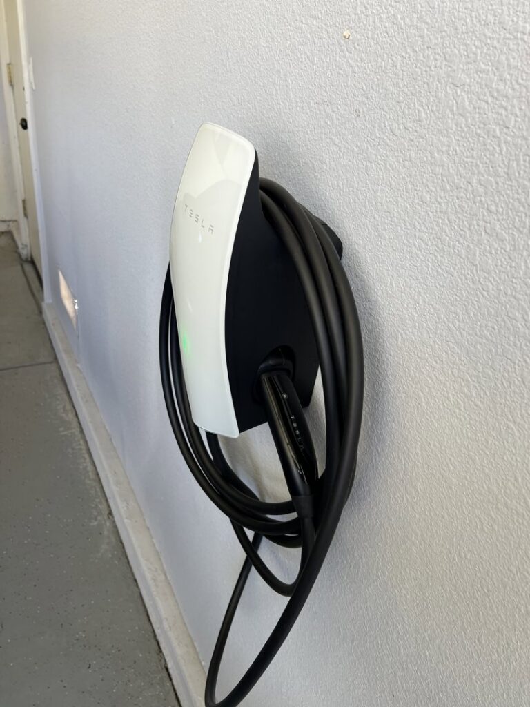 A Tesla EV charger professionally installed on a garage wall, ready for use, by AAA Electrical Services in Sacramento, CA.