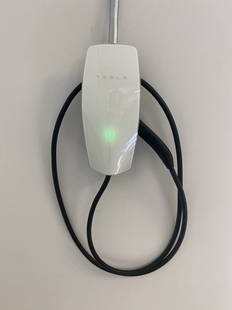 A Tesla EV charger professionally installed on a wall by Power Tech Electrical Services in Durham, NC.