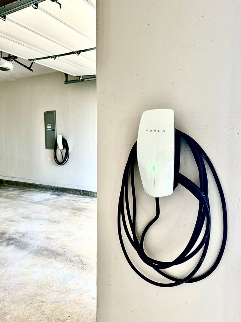 A close-up of a Tesla electric vehicle charger installed on a garage wall by Premier Power in Edmond, OK.