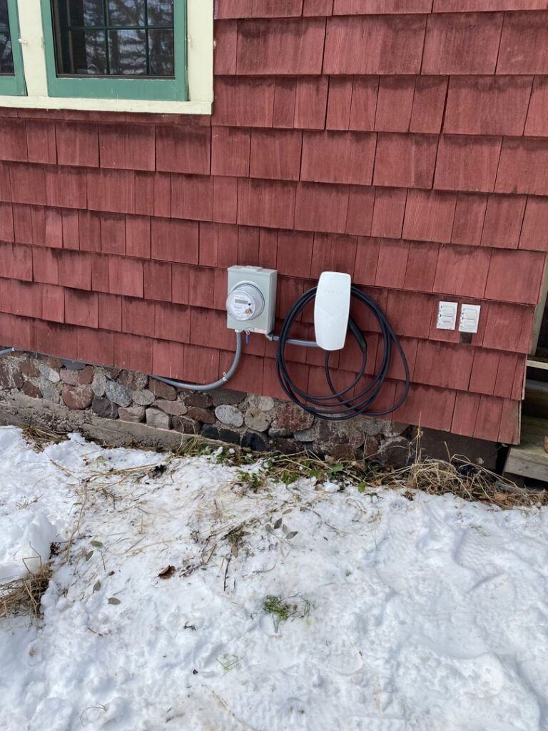 A Tesla EV charger and electrical meter installed on the exterior of a home by Schroeder Electric in Duluth, MN.