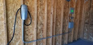 A Tesla EV charger installed on a wooden wall in a garage by Star Light Electric LLC in Phoenix, AZ