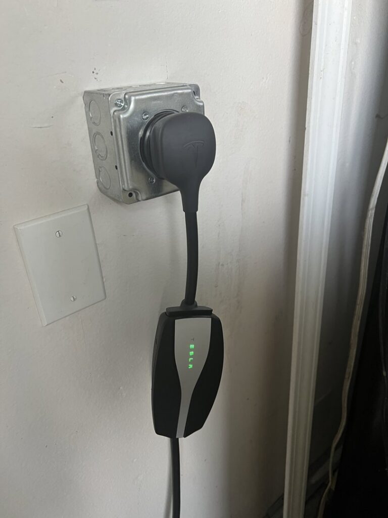 A Tesla electric vehicle charger professionally installed on a wall by Steve Cavenee Electric in Orange, CA.