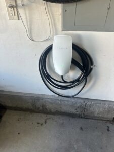 A Tesla electric vehicle charger professionally installed on a garage wall by The Electric Way in Colorado Springs, CO.