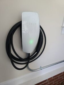 A Tesla EV charger installation with conduit on a wall by TOTAL Electric LLC in Fayetteville, NC.