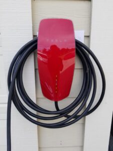 A red Tesla electric vehicle charger professionally installed on a home exterior by Wisdom Electrical in San Francisco, CA.