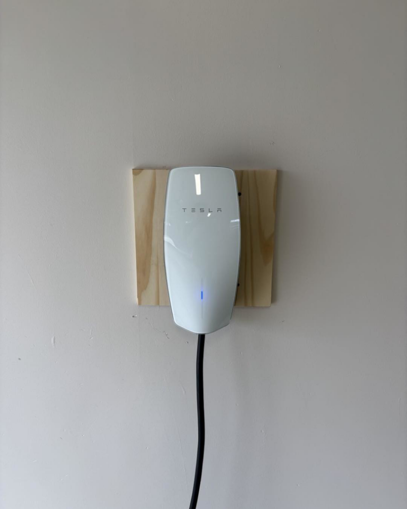 A newly installed Tesla electric vehicle charger on a wall by Zimmerman Electric Indy in Indianapolis, IN