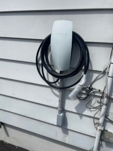A newly installed Tesla electric vehicle charger on a residential exterior wall by Ruben's Electric in Harlingen, TX