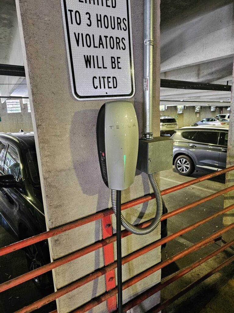 A Tesla EV wall connector charging station installed in a parking garage by 8Thirty Electric, Inc. in Johns Creek, GA.