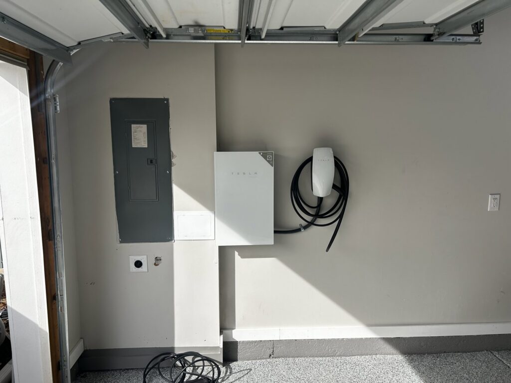 A Tesla Powerwall and EV charger installed next to an electrical panel by Prime Time Electric in Rock Hill, SC.