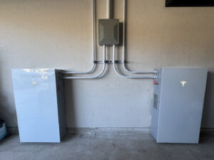 Tesla Powerwall units installed on a garage wall with electrical conduit by Omni Power Electrical Services LLC in San Antonio, TX