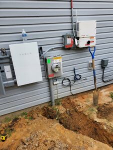 A Tesla Powerwall and electrical meter installation with a trench by Tim Lambert Electric in Fayetteville, NC.